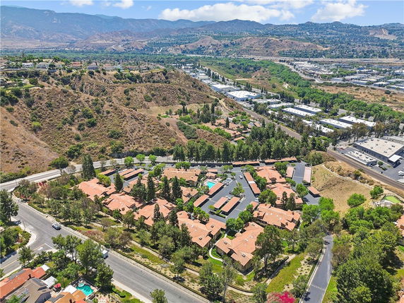 Aerial view of a residential area with homes, roads, and surrounding hills and commercial buildings.