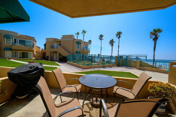 View of a patio area overlooking a beachside apartment complex with ocean in the background.
