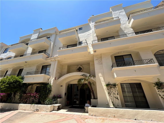 Front view of a multi-story building with balconies and arched entrance.