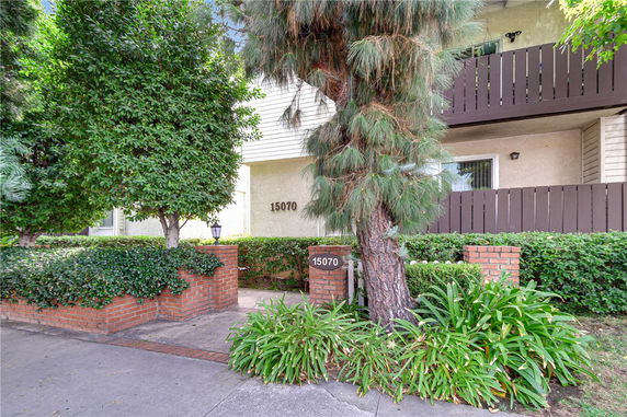Front view of a building with a brick entrance and surrounding greenery.