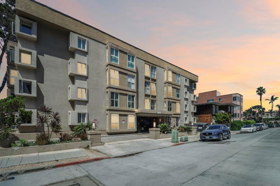 Front view of a multi-story apartment building with rectangular windows and a beige facade.