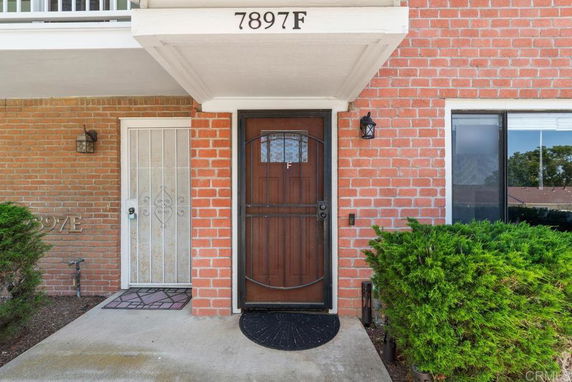 Front view of a brick house entrance with a wooden door and address number 7897F.