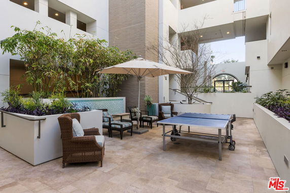 Indoor recreational area with seating, plants, and a ping pong table.