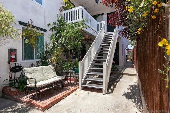Front view of a two-story building with an outdoor staircase and garden area.