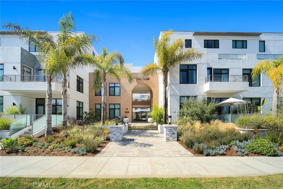 Front view of a modern multi-story building with a landscaped entrance.