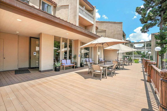 Outdoor seating area on the deck of a building with multiple floors.