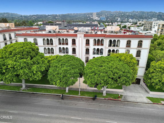 Front view of a multi-story residential building with arched windows and a red-tiled roof.