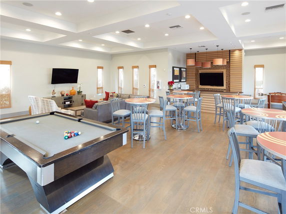 Interior view of a clubhouse with billiards table, seating area, and television.