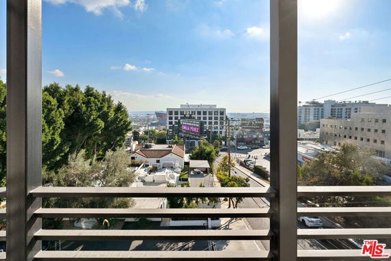 Panoramic view from a balcony overlooking a cityscape with buildings and trees.