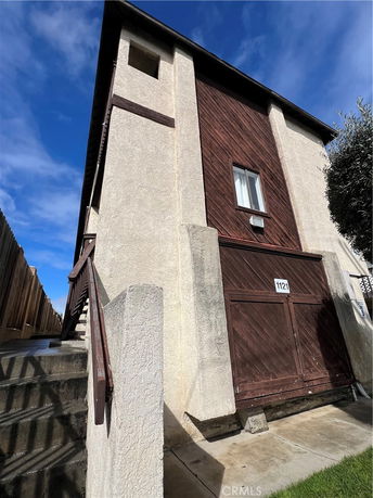 Side view of a building with textured stucco exterior and wooden paneling.