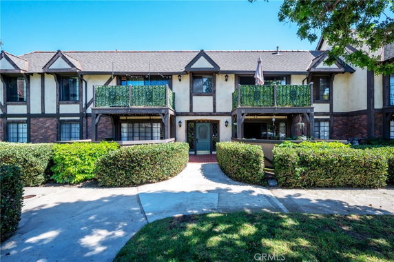 Front view of a two-story house with a Tudor-style design and balconies.