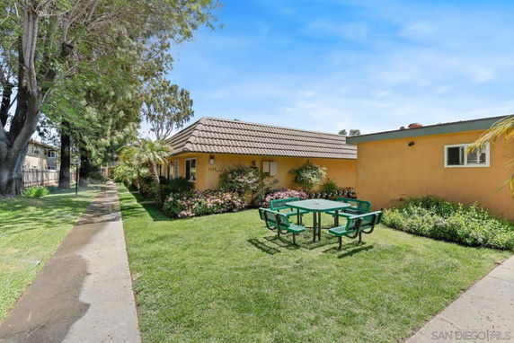 View of a single-story building with a tiled roof and a green lawn area with a picnic table.