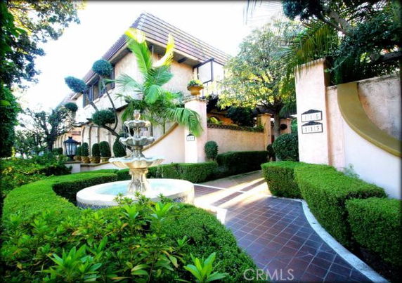 Front view of a house with a fountain and landscaped garden.