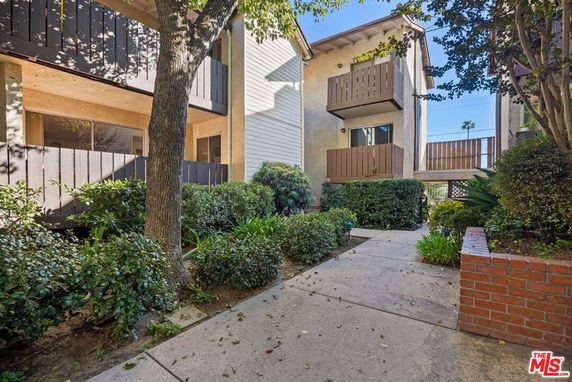 Front view of a residential apartment building with balconies and surrounding greenery.