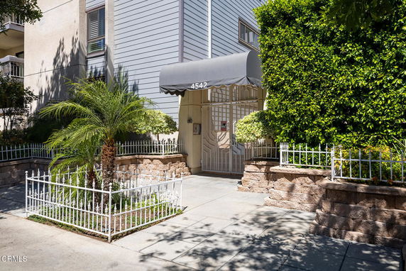 Front view of a multi-story building with a gated entrance and canopy.