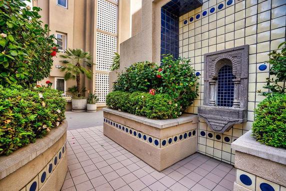Outdoor view of a decorative area with tiled walls, potted plants, and a water feature.