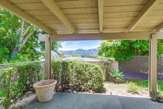 View from a covered patio overlooking greenery and hills in the distance.