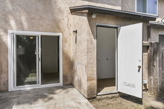 Back view of a house with sliding glass door and a single side door.