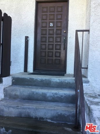 Front view of a building entrance with a wooden door and concrete steps.