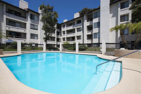 Outdoor swimming pool in front of a multi-story residential building.