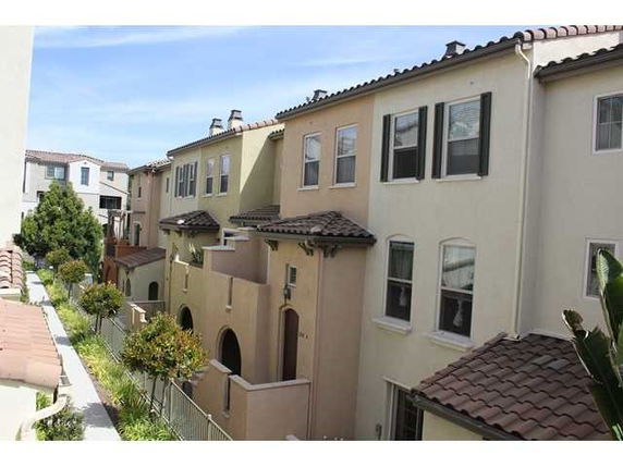Front view of a row of two-story townhouses with tiled roofs and small balconies.