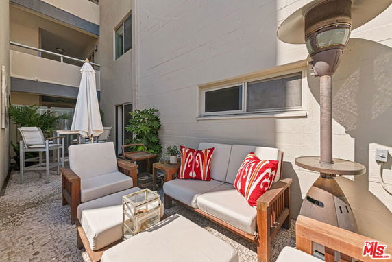 Outdoor seating area with wooden furniture and patio heater against a building wall.