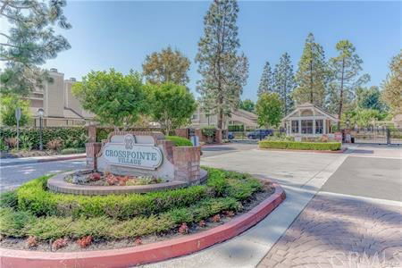 Front view of a residential entrance with a sign reading 'Crosspointe Village' and a security gate.