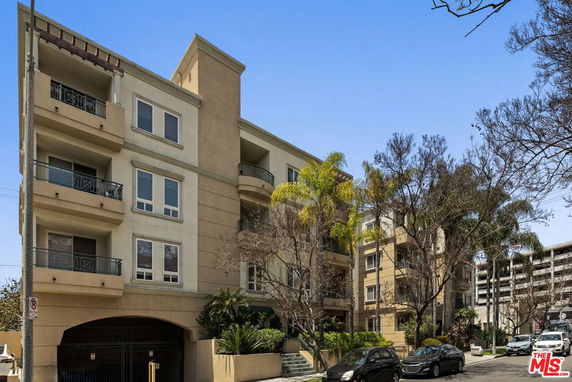 Front view of a multi-story apartment building with balconies and an arched entrance.