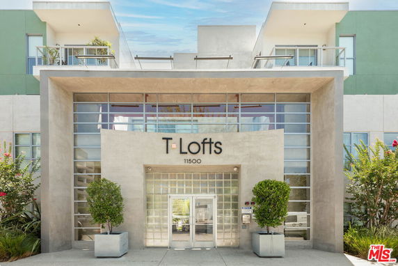 Front view of a modern building with glass and concrete facade displaying the name 'T-Lofts'.