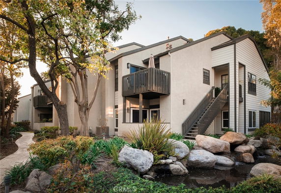 Front view of a two-story residential building with balconies and stairs.