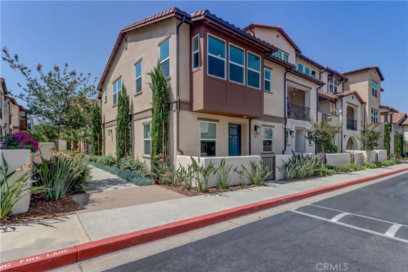 Front view of a multi-story townhouse with a landscaped pathway and balcony.