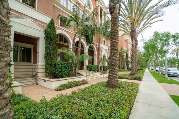 Front view of a multi-story building with arched entrances and palm trees.