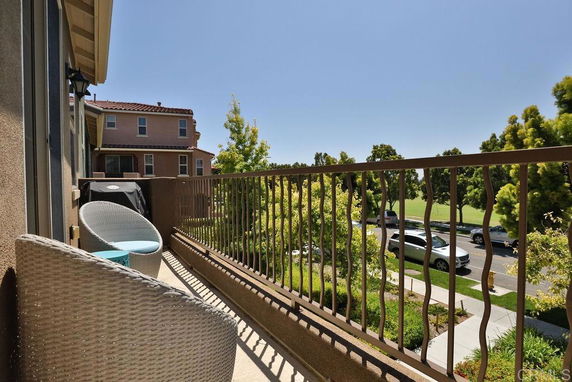 View from a balcony showing nearby houses and a tree-lined street.