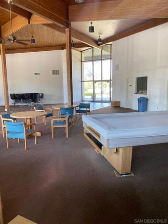 Interior view of a recreational area with wooden ceiling, seating area, and a covered pool table.