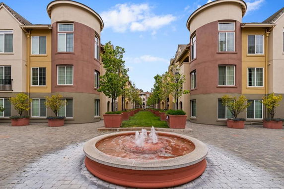 Front view of a multi-story residential building with round towers and courtyard.