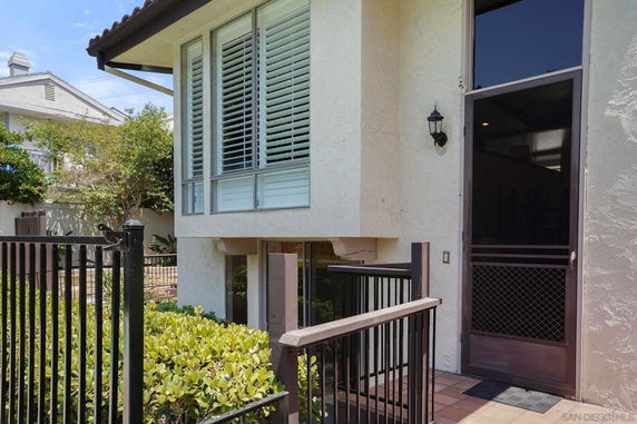 Front view of a house with large windows and a screen door entrance.