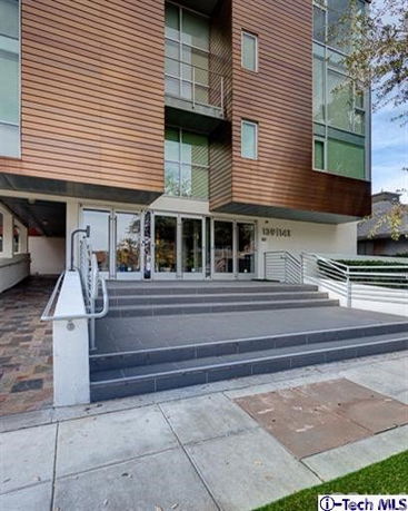 Front view of a modern multi-story building with a wooden facade and glass windows.