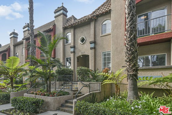 Front view of a multi-story residential building with stucco exterior and tiled roof.