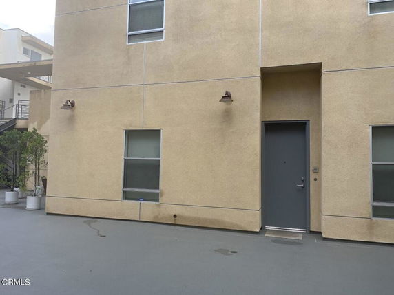 Front view of a building entrance with beige walls and two windows.