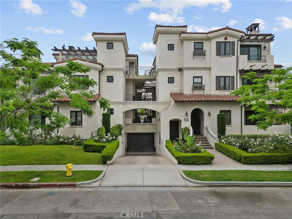 Front view of a multi-story residential building with balconies and Spanish-style roofing.