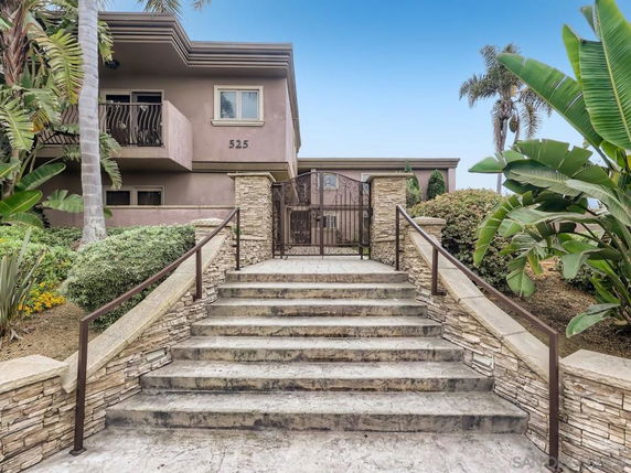 Front view of a two-story building with a stone staircase and metal gate entrance.