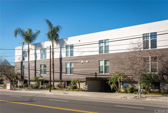 Front view of a modern three-story building with a white and wood exterior.