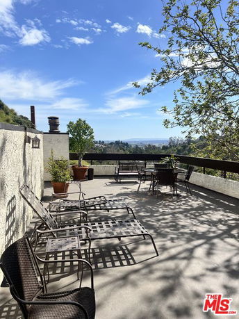 Rooftop patio with outdoor furniture and view of distant landscape.