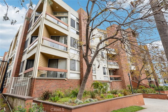 Front view of a multi-story building with balconies and brick exterior walls.