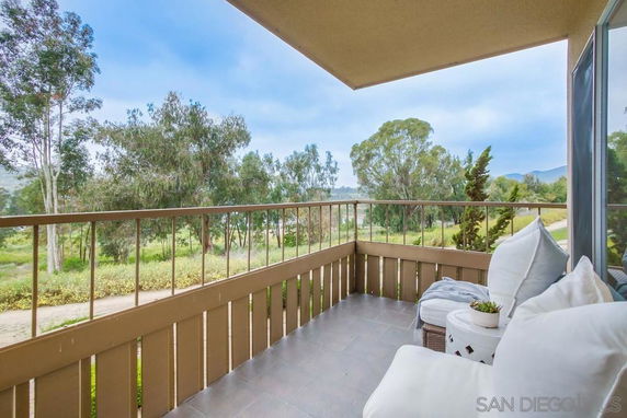 Balcony view overlooking trees and distant hills.