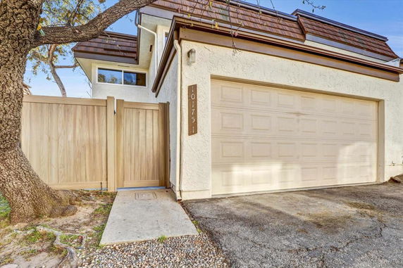 Front view of a house with a two-car garage and wooden gate.