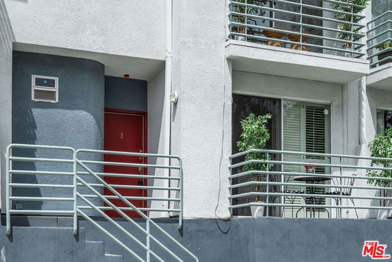 Front view of a building with balconies and a red door entrance.