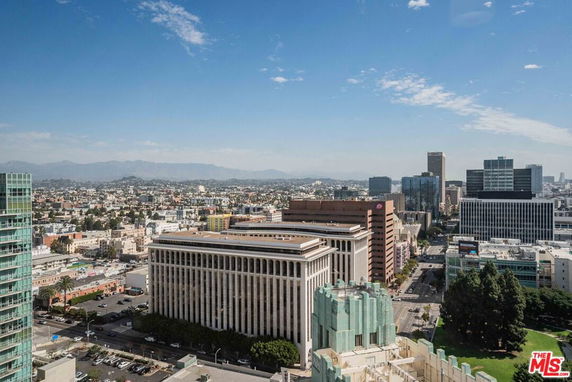 Panoramic view of a cityscape with tall buildings and mountains in the background.