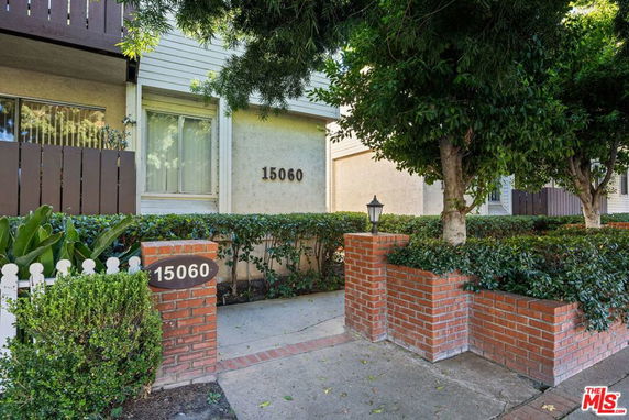 Front view of a residential building with brick pillars and hedges.