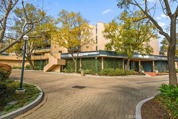 Front view of a multi-story building with exterior staircase and surrounding trees.